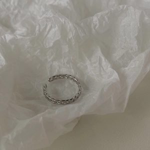 Dettaglio di un anello regolabile a catena d'argento su sfondo di carta bianca testurizzata