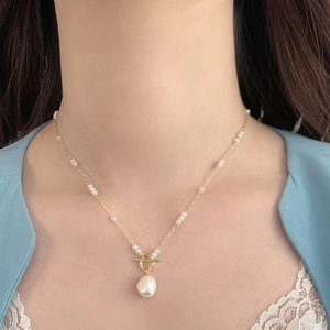 Gold chain necklace with freshwater pearls and toggle clasp worn by a model