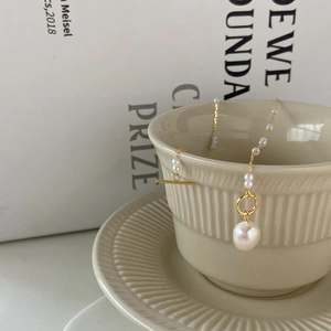Detail of freshwater pearl necklace with golden OT toggle clasp on a vintage cup