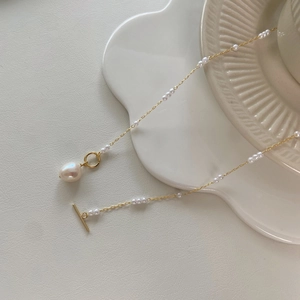Macro detail of OT buckle necklace with golden chain and baroque pearl pendant