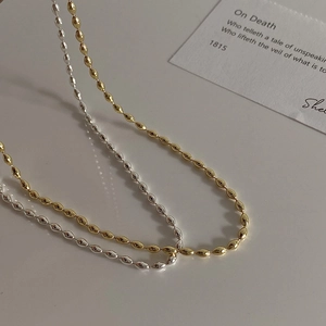 Detailed view of polished gold and silver small olive bead necklaces with a metallic finish