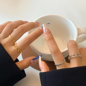 Set di anelli a catena cubana oro e argento da donna esposti su un tavolino