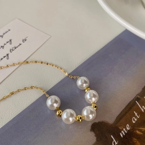 Detail showing five white pearls with gold spacers on a fine gold chain necklace