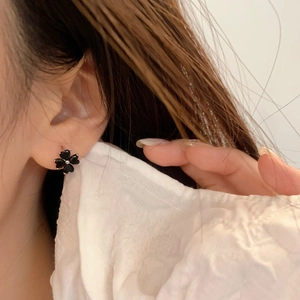 Close-up of heart-shaped black gemstone clover stud earrings worn on earlobe