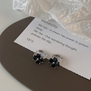 Close-up of vintage black four-leaf clover drop earrings with silver finish and crystal inlay