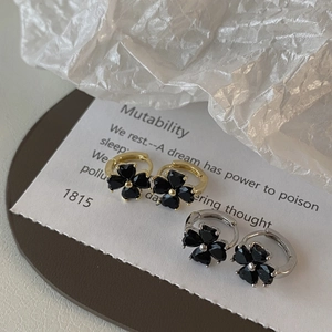 Detail of four-leaf clover drop earrings with black heart-shaped stones in gold and silver