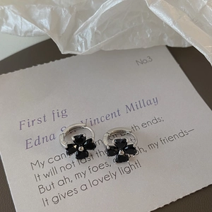 Detailed view of silver clover hoop earrings with black faceted gemstone inlays