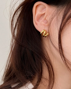 Detail of triple-layered golden spiral hoop earrings worn by a model