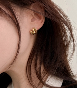 Close-up of triple-layered gold-plated loop earrings worn by a model in a minimalist style