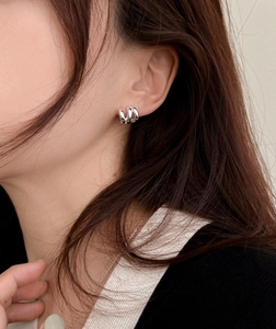Detail of silver triple-layered hoop earrings with a polished minimalist metallic finish