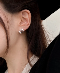 Close-up of small silver multi-layer metal hoop earrings with a textured thick design