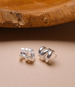 Close-up of silver triple-layered spiral stud earrings with elegant metal texture