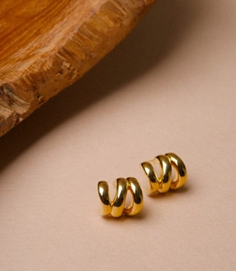 Detail of gold triple-layered spiral stud earrings with a polished metallic finish