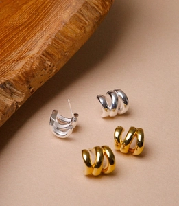 Detailed view of polished multi-layer spiral C-shape hoop earrings in gold and silver finish