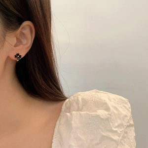 Elegant black clover stud earring with gold border shown on a model for a minimalist look