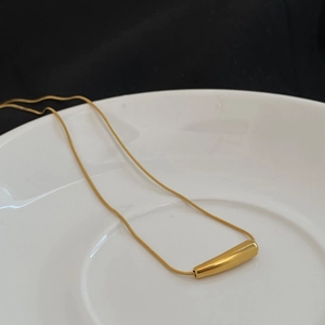 Nahaufnahme der minimalistischen goldenen Schlangenkette mit glattem Tropfenanhänger