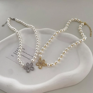 Détail de colliers avec pendentifs floraux et perles en finitions or et argent sur plateau