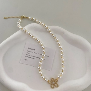 Détail du collier fleur avec perles brillantes et strass étincelants sur chaîne dorée