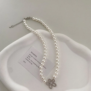 Détail d'un collier de perles avec pendentif fleur serti de diamants sur plateau pierre