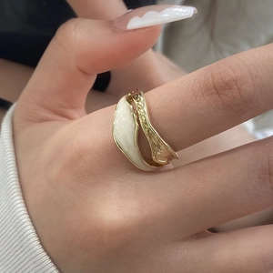 Modern irregular gold-plated ring with white enamel and hammer texture on model hand
