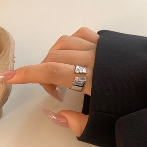 Detailed view of an adjustable silver ring with zircon stones worn on a model finger