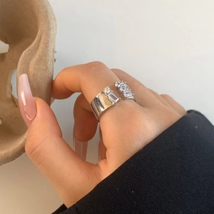 Detailed close-up of an adjustable silver ring with zircon stones on a model's hand