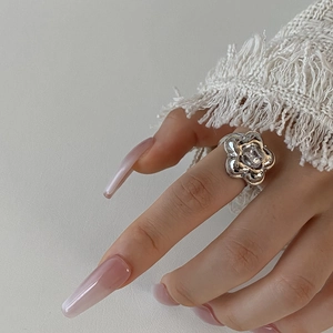 Detail of silver flower ring with large oval zircon on hand with gradient nails