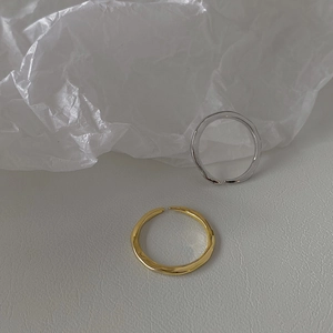 Detail of minimalist wavy adjustable rings in gold and silver finish with smooth texture