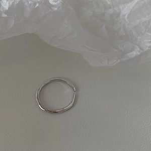 Detailed close-up of adjustable silver ring with irregular wave texture on leather background