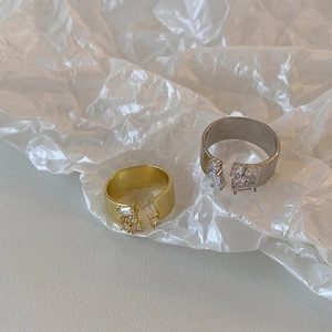 Minimalist gold and silver open rings with zircon clusters on white paper background