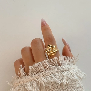 Golden flower ring with crystal center on female hand with white sleeve background