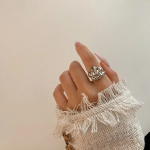 Silver flower ring with center square zircon shown on hand against tweed sleeve