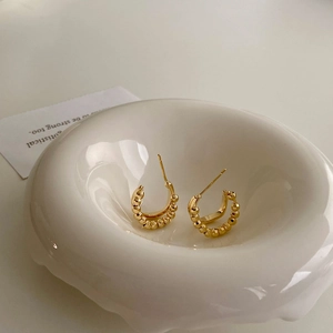 Detailed macro view of irregular geometric golden hoop earrings with beaded texture