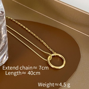 Detail of gold spliced chain necklace with circular pendant on a brown leather tray