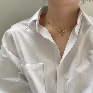 Close-up of double layer gold necklace with circular pendant on a white shirt