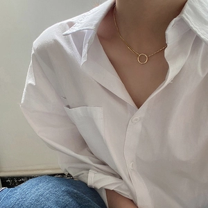 Detail of gold spliced clavicle chain necklace with a circular ring pendant on model
