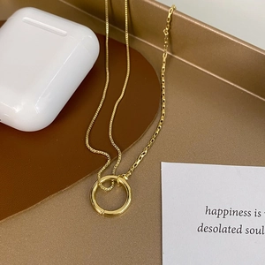 Detail of gold spliced chain necklace with a minimalist round pendant on leather background