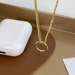Detail of gold double-layer necklace with a polished ring pendant on a brown pad
