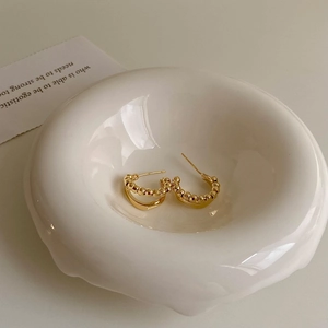Minimalist irregular double-layer gold C-shaped earrings with bead texture in a ceramic dish