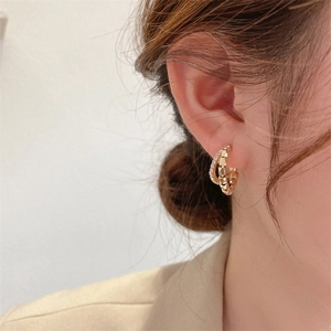 Close-up of double-layered gold-plated C-shaped earrings with shimmering crystals on model
