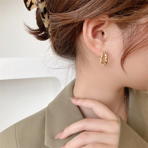 Double-layered gold twisted hoop earrings with shimmering crystals worn by a model