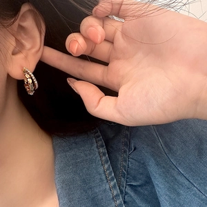 Detail of double-layer gold hoop earrings with glitter texture worn on the ear