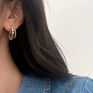 Close-up of double-layer gold hoop earrings with pavé crystals on a model's ear