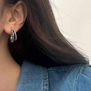 Close-up of double-layer silver ear hoop featuring geometric cuts and sparkling zircons