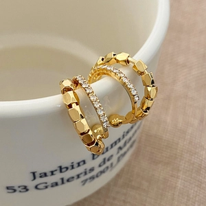 Close-up of three-piece gold-plated earring set with pave zircon on a porcelain cup edge