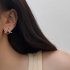 Close-up of elegant silver ribbon twist earrings with sparkling pave zircon stones