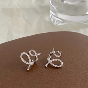 Detailed macro view of silver cross-line stud earrings with sparkling zircon inlay