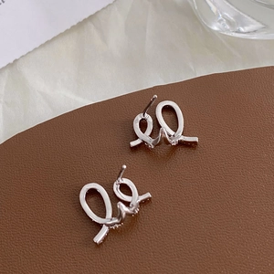 Detailed view of silver twist stud earrings with sparkling pavé zircons on leather