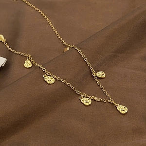 Detail of gold coffee bean necklace on brown silk fabric with minimalist organic pendants