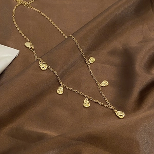 Minimalist gold coffee bean necklace with irregular hammered charms on a silk background